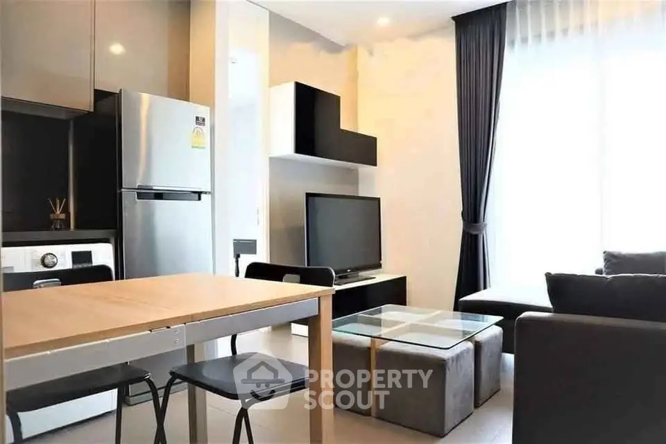 Modern living room with sleek furniture and natural light, featuring a stylish kitchen area.
