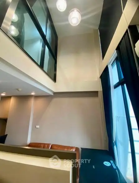 Modern loft-style living room with high ceilings and large windows