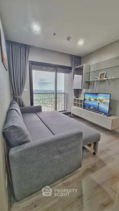 Modern living room with gray sofa, TV, and balcony view in stylish apartment.