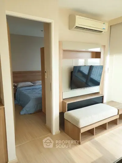 Modern apartment interior with cozy bedroom and stylish living area featuring a mounted TV and air conditioning.