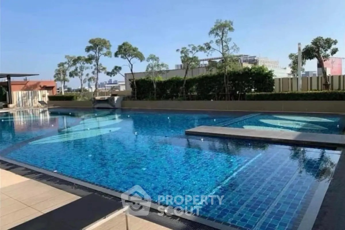 Luxurious outdoor swimming pool with city skyline view, perfect for relaxation and leisure in a modern residential complex.