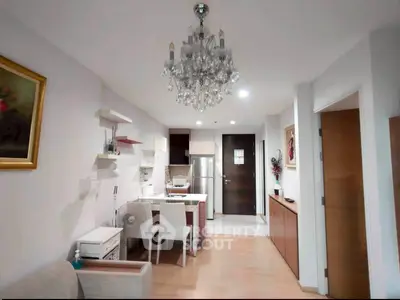 Modern open-layout kitchen and living area with elegant chandelier and stylish decor.
