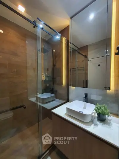 Modern bathroom with glass shower and elegant vanity in luxurious home.