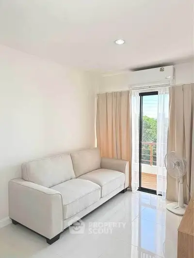 Bright living room with cozy sofa and balcony view in modern apartment.