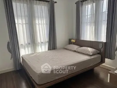 Cozy bedroom with natural light and elegant curtains, perfect for relaxation and comfort.