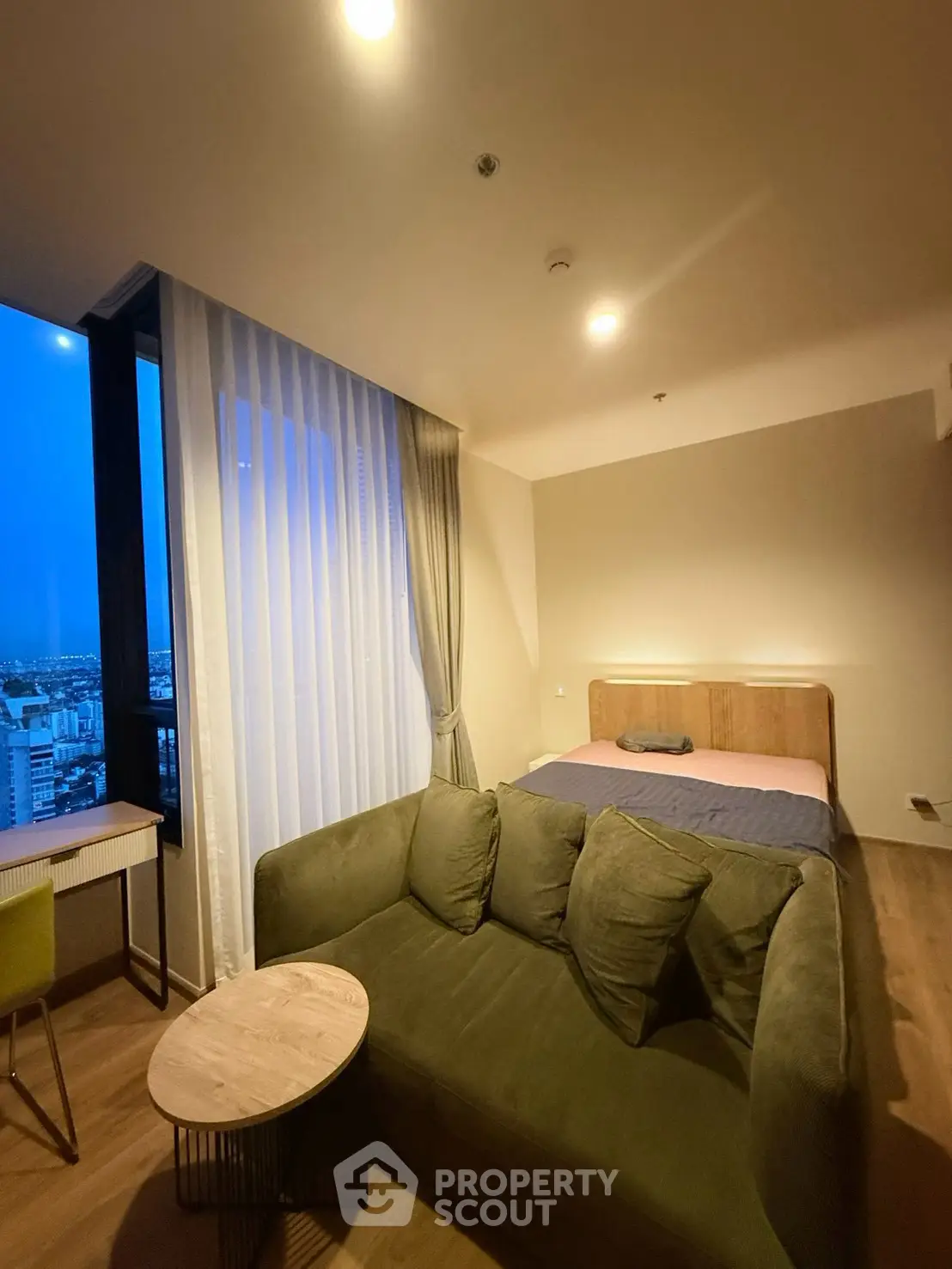 Modern studio apartment with cozy living area and city view, featuring a comfortable bed and stylish decor.