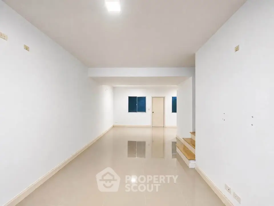 Spacious open-plan living area with glossy tiled floors and modern staircase.