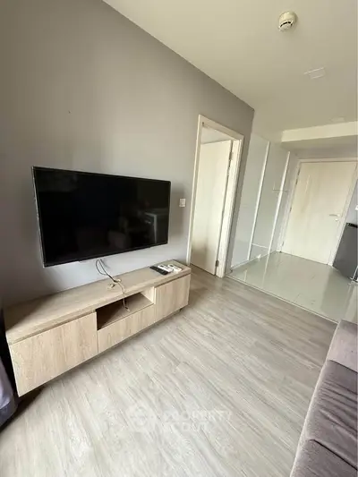 Modern living room with sleek TV setup and wooden flooring in a stylish apartment.
