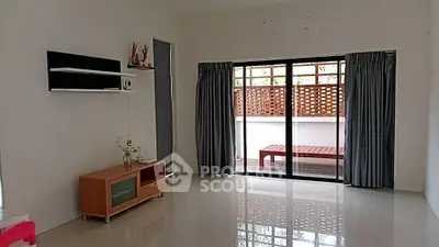 Spacious living room with sliding glass doors leading to a private balcony, featuring modern decor and ample natural light.