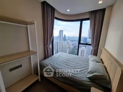Modern bedroom with stunning city view from large window in high-rise apartment.