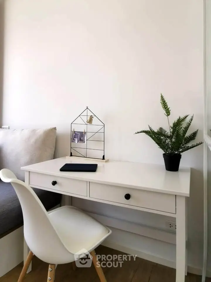 Modern study nook with sleek white desk, stylish chair, and decorative plant for a serene workspace.
