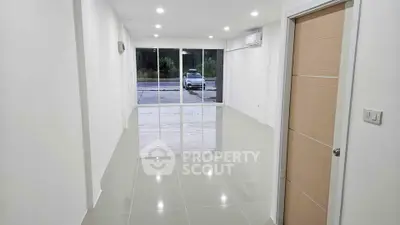 Spacious modern living room with glossy tiled floors and large windows offering natural light.