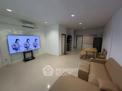 Spacious living room with modern furniture and large TV, ideal for relaxation and entertainment.