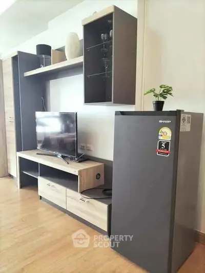 Modern living room with sleek TV stand and compact refrigerator, perfect for urban living.