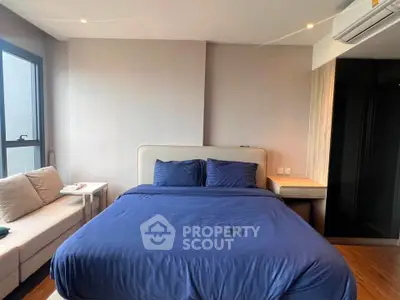 Modern bedroom with blue bedding and natural light in a stylish apartment.