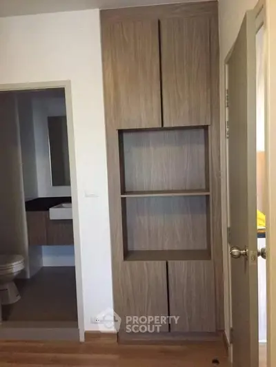 Modern interior with sleek wooden storage and bathroom view, perfect for compact living spaces.
