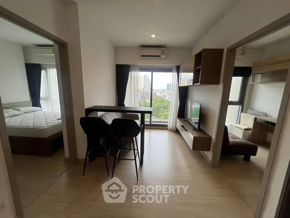 Modern apartment interior with open living area and city view, featuring stylish furniture and natural light.