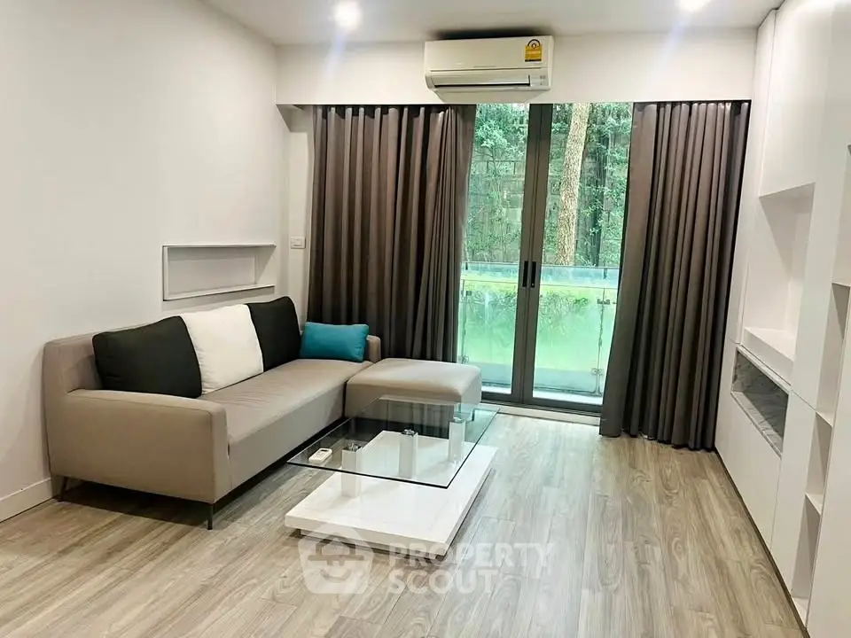 Modern living room with sleek design and large windows overlooking greenery.
