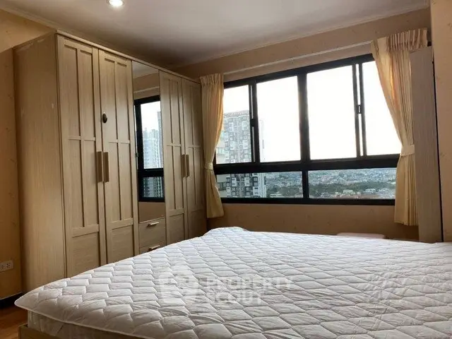 Spacious bedroom with large windows offering stunning city views and ample natural light.