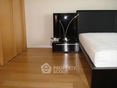 Modern bedroom with sleek furniture and wooden flooring, featuring a stylish bed and nightstand.