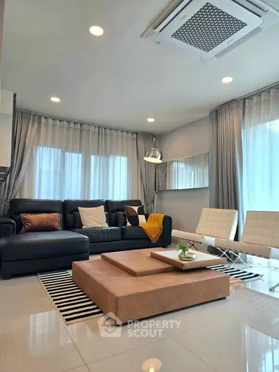 Modern living room with stylish furniture and large windows, featuring a cozy ambiance and elegant decor.