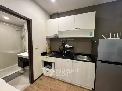 Modern compact kitchen with sleek cabinets and appliances in a cozy apartment setting.
