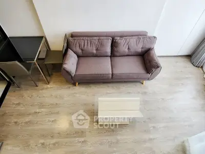 Modern living room with stylish sofa and glass coffee table on wooden flooring.