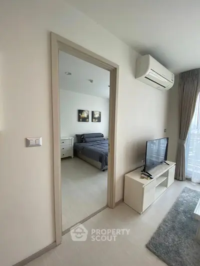 Modern apartment interior with cozy living room and view into stylish bedroom.