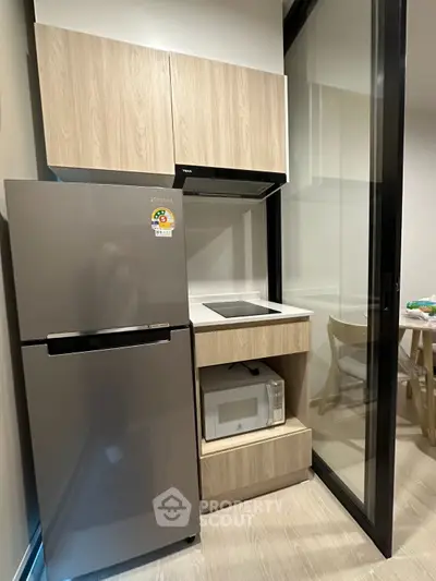 Modern compact kitchen with sleek appliances and wooden cabinetry, perfect for urban living.