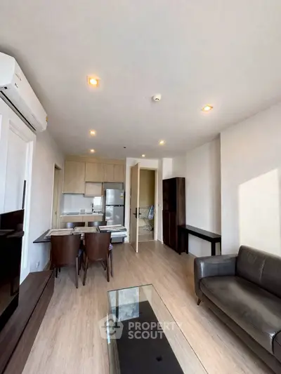 Modern living room with open kitchen, sleek furniture, and natural light in a stylish apartment.