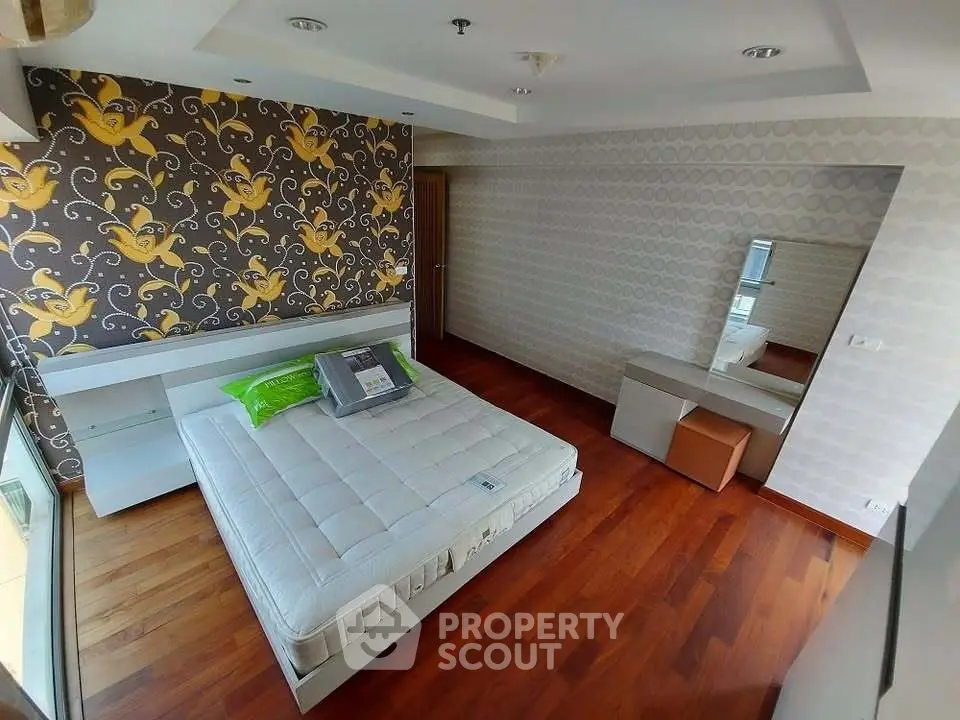 Spacious bedroom with modern decor and hardwood floors in a stylish apartment.