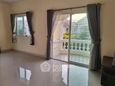 Spacious living room with large windows and balcony access, offering ample natural light and elegant curtains.
