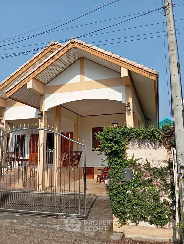 Charming single-story house with gated entrance and lush greenery, perfect for cozy living.