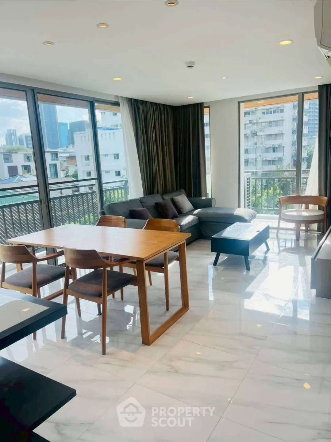 Spacious modern living room with large windows and city view, featuring elegant furniture and natural light.