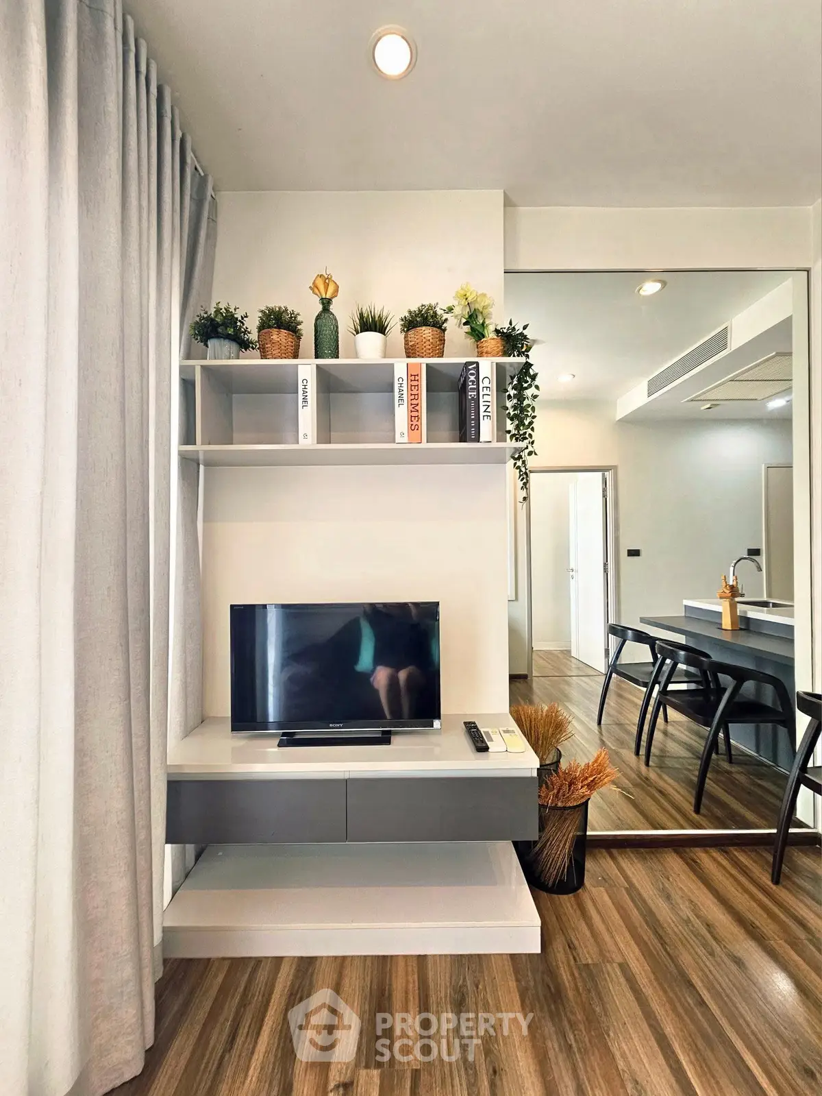 Modern living room with stylish decor, wall-mounted TV, and elegant wooden flooring.
