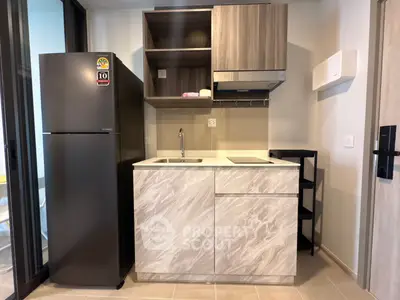 Modern compact kitchen with sleek cabinetry and stainless steel fridge in a stylish apartment.