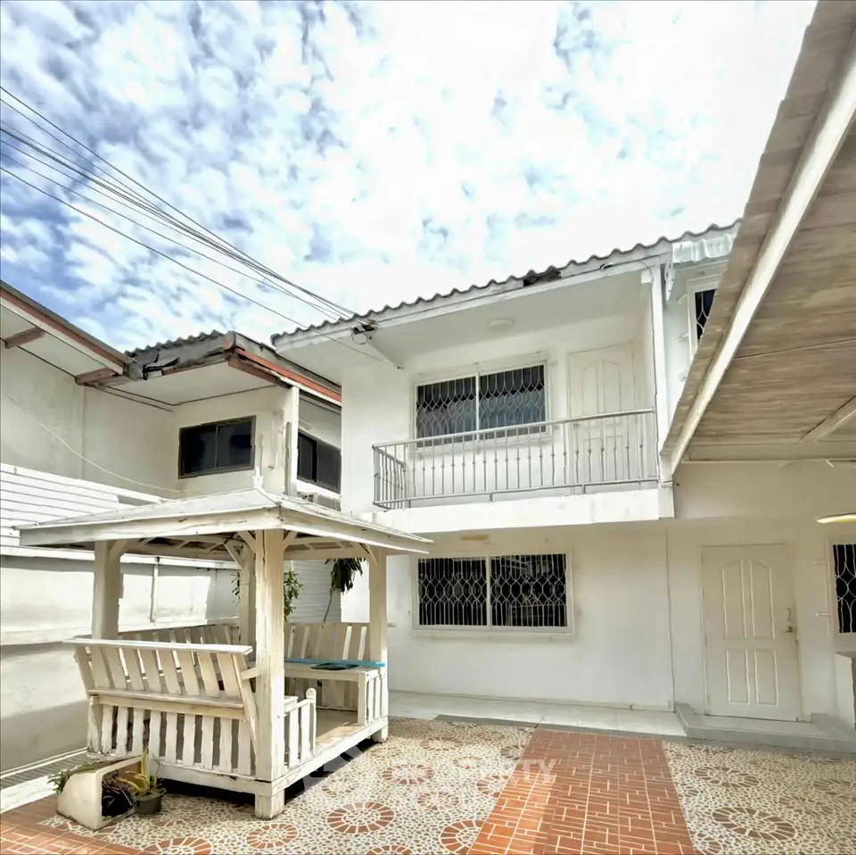 Charming white two-story house with a cozy patio and traditional tile flooring.