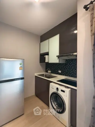 Modern compact kitchen with washing machine and fridge in sleek design.