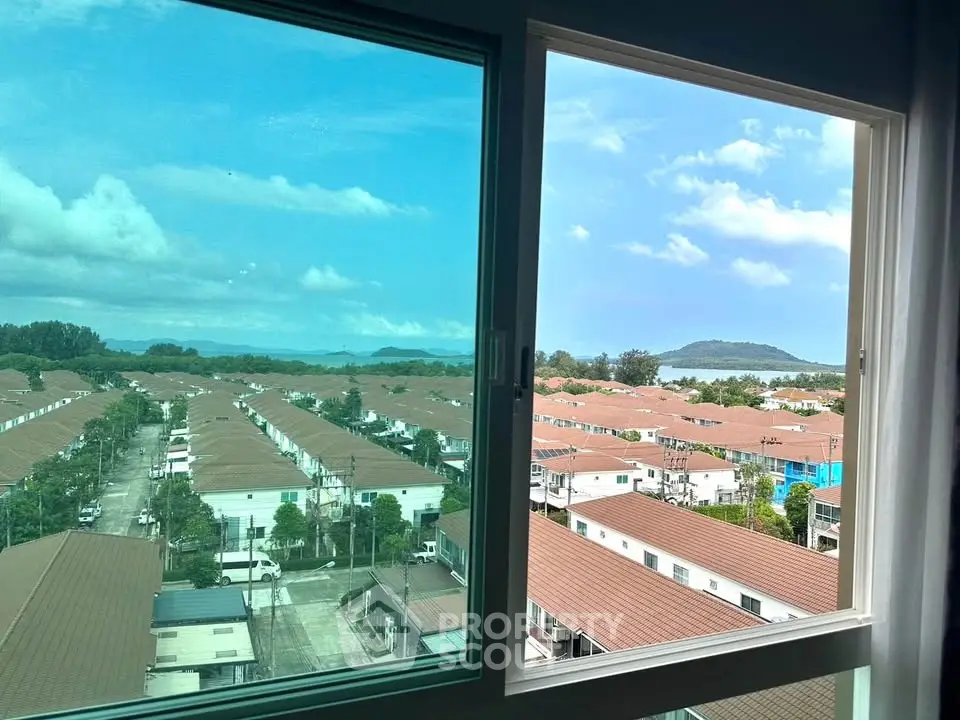 Stunning view from a high-rise window overlooking a suburban neighborhood and distant hills.