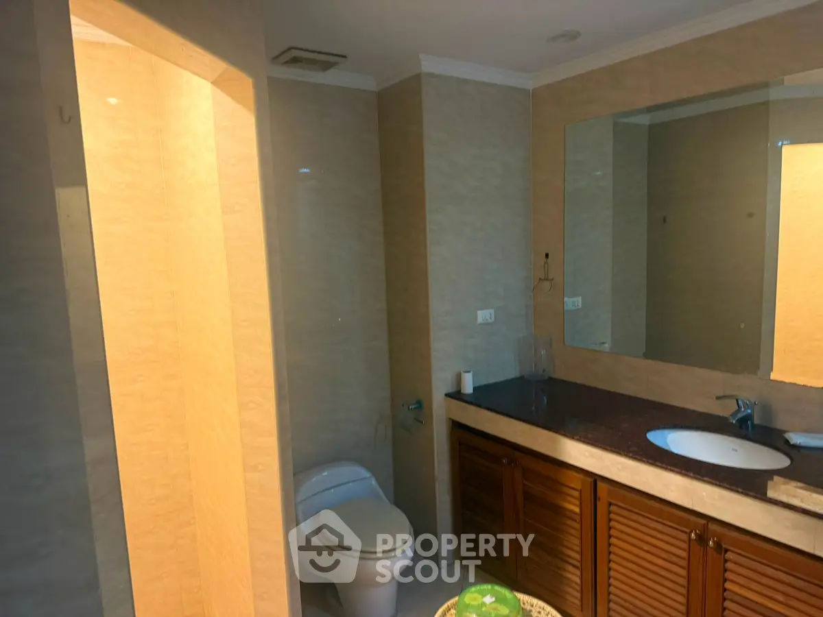 Spacious bathroom with elegant wooden cabinetry and large mirror, featuring modern fixtures and neutral tones.