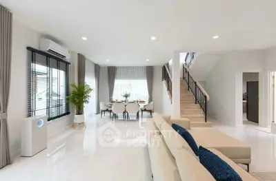Spacious modern living room with elegant dining area and staircase, featuring sleek design and ample natural light.