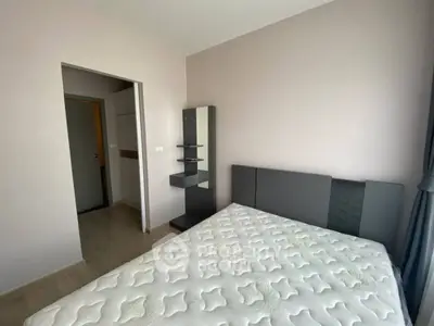 Modern bedroom with stylish decor and natural light, featuring a comfortable bed and sleek shelving unit.