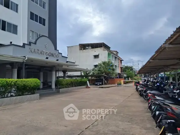 Modern apartment building exterior with parking area and lush greenery.