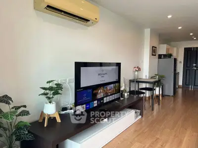 Modern living room with sleek TV setup and stylish decor in open-plan apartment.