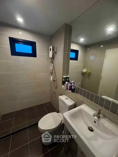 Modern bathroom with sleek fixtures and large mirror, featuring a shower and toilet.