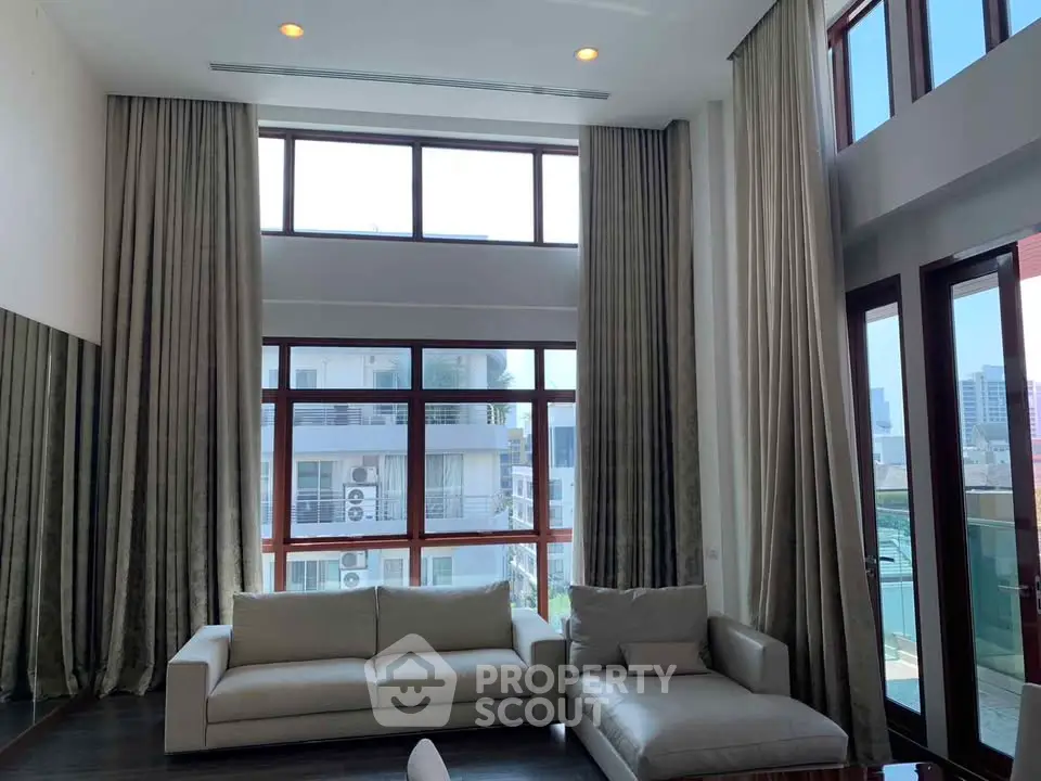 Spacious living room with high ceilings and large windows offering abundant natural light and city views.