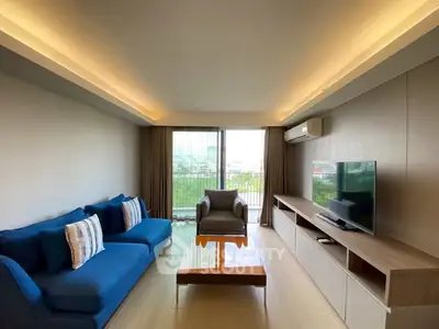 Modern living room with blue sofa, large TV, and balcony view in a stylish apartment.