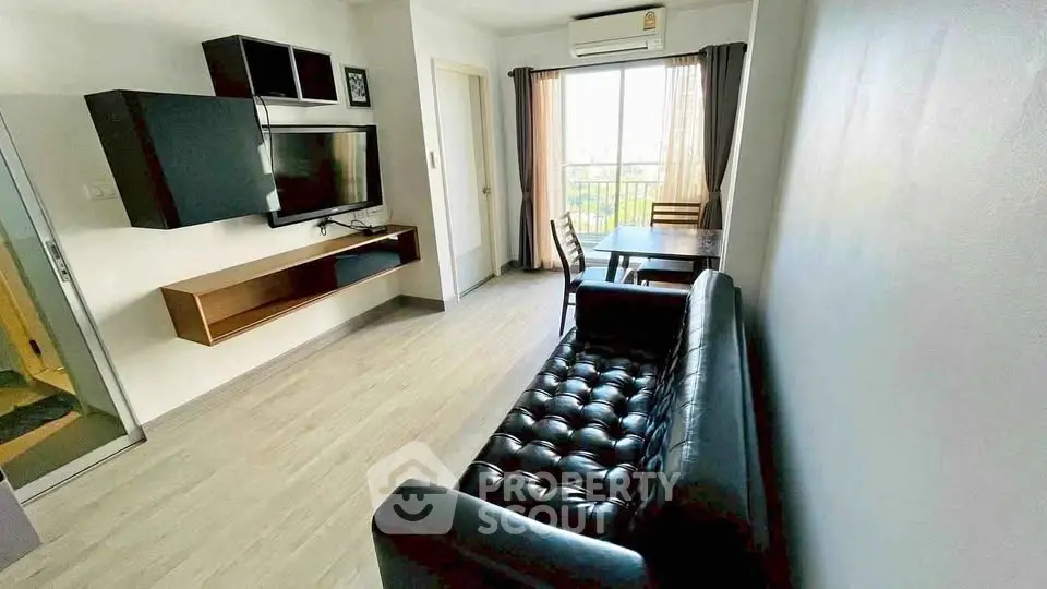 Modern living room with sleek black leather sofa and wall-mounted TV, featuring a dining area by the window.