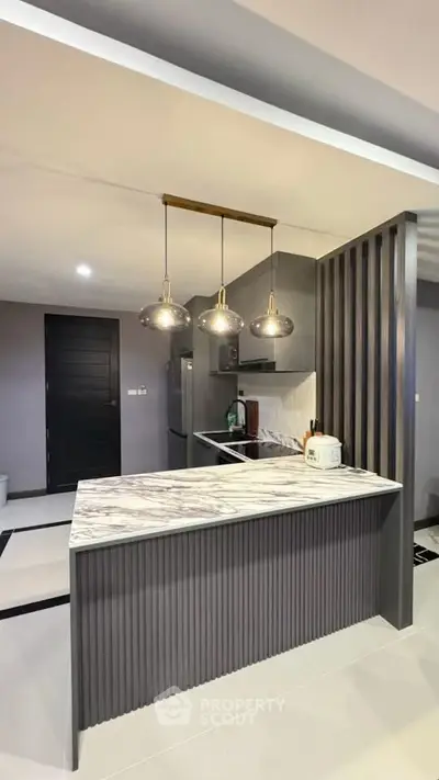 Modern kitchen with marble island and pendant lighting in sleek apartment