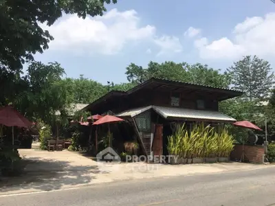 Charming rustic house with lush greenery and outdoor seating, perfect for serene living.